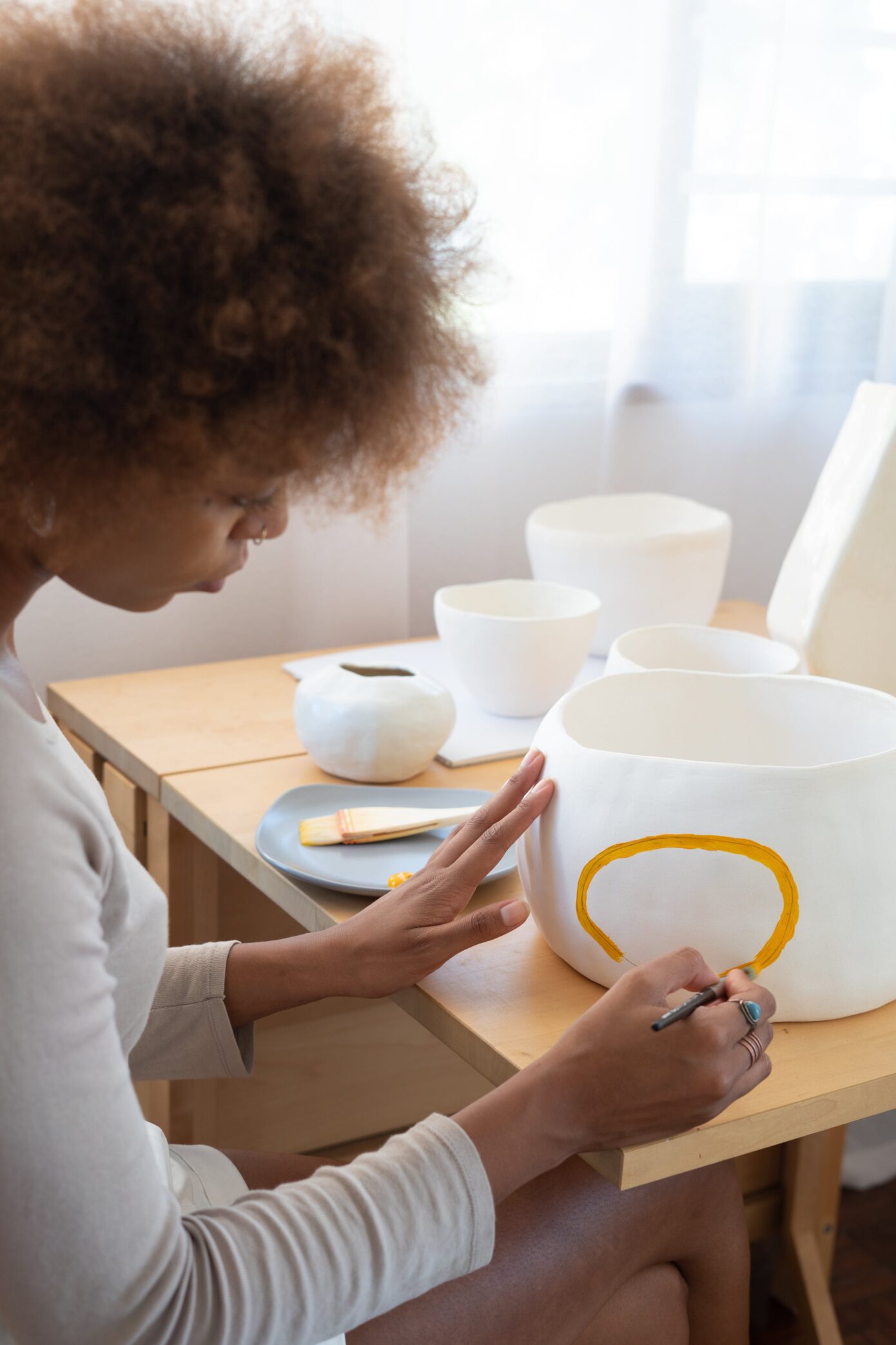 woman applying glaze to piece